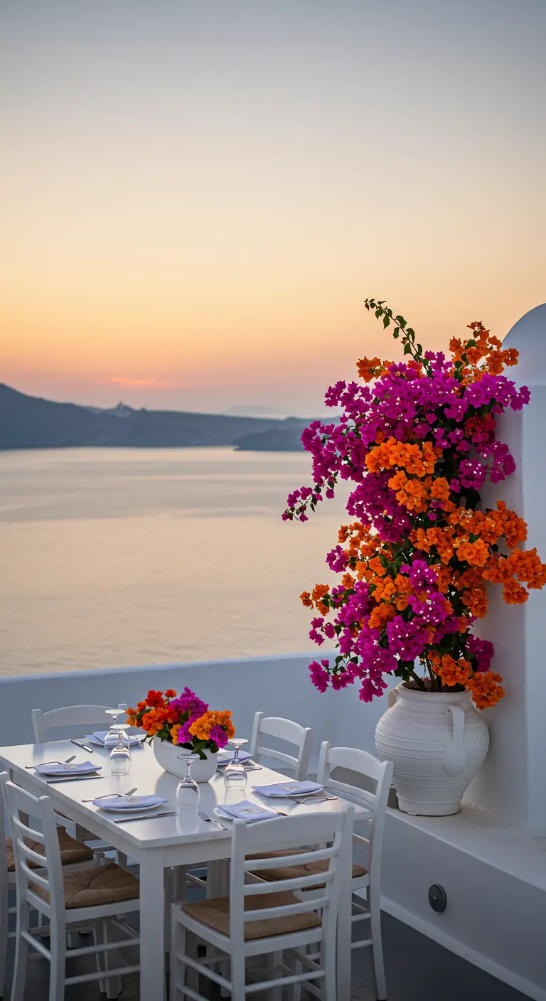 Table blanche sur un balcon avec vue mer, à côté d'un bougainvillier fuchsia et orange.