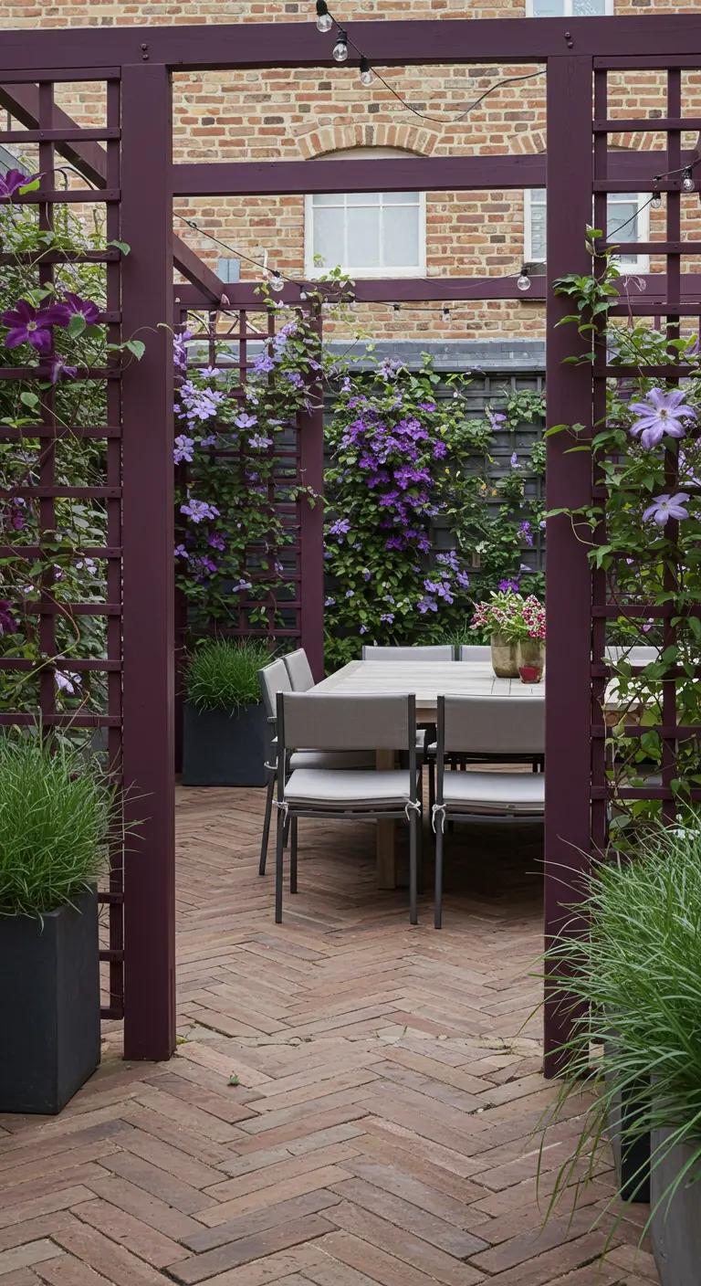 Passage de pergola en treillis prune avec des clématites violettes, menant à une table à manger d'extérieur.