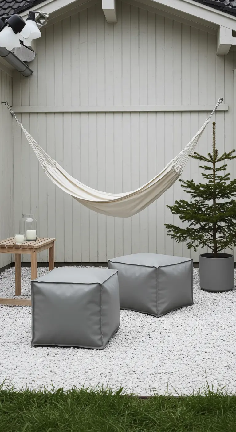 Hamac blanc et poufs gris sur un parterre de gravier blanc.